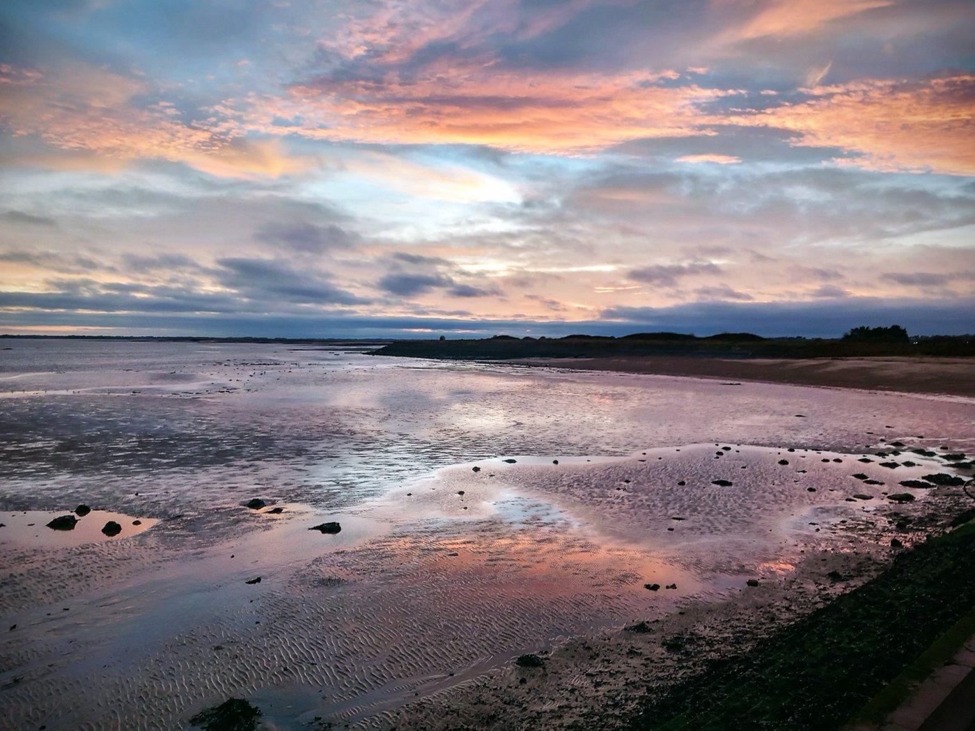 Soft pink evening sky reflected across a peaceful shoreline