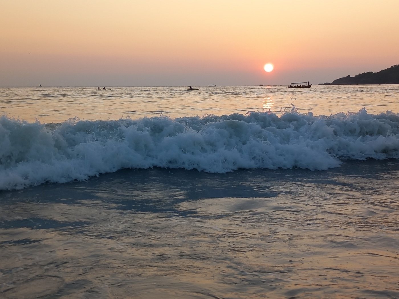 A gentle wave at sunset with a warm peach sky